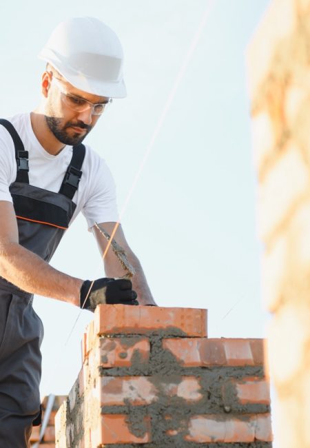 Construction worker in uniform and safety equipment have job on building. Industrial theme.